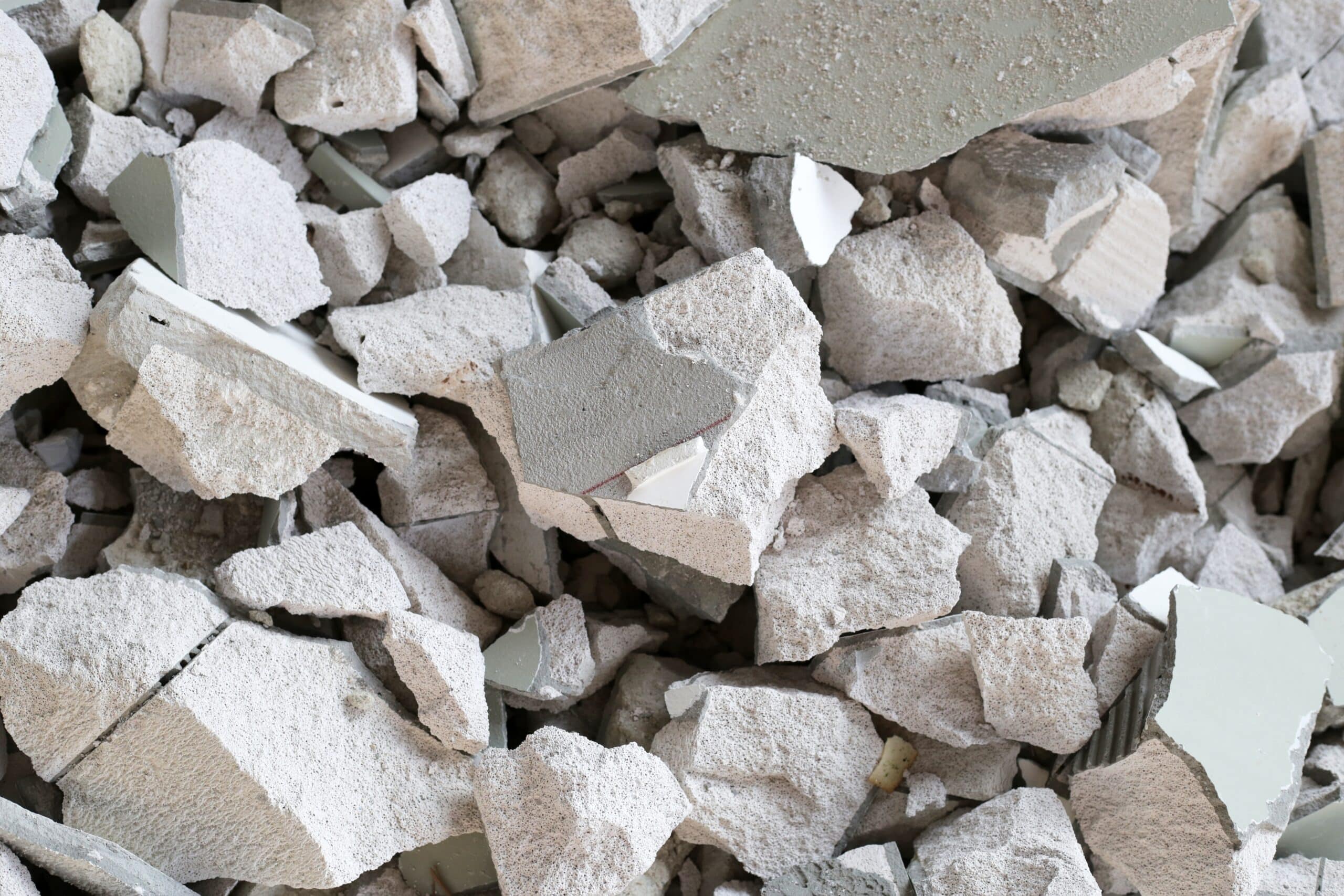 Gros plan de décombres et gravats de béton cellulaire blanc cassés sur un chantier de démolition.